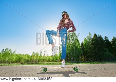 Cool modern teen girl rides a longboard on a highway outside the city. The spirit freedom and autumn adventures. 