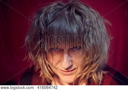Portrait Of Tousled Disheveled Middle-aged Woman Looking Like A Madwoman On Red Background In Studio