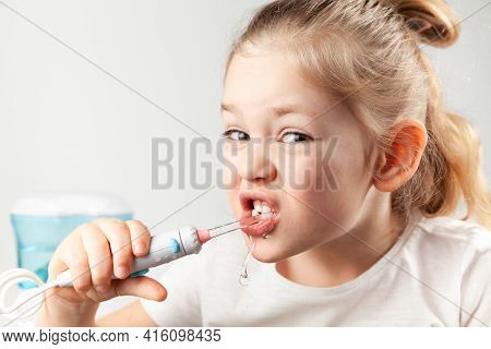 Water Flosser. Girl Child Cleans His Teeth, Care For The Oral Cavity In Childhood.