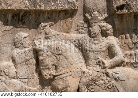 Murals Of Necropolis, King Burial Site Of Ancient Persia. King On His Horse Carved Into Sandstone Ro