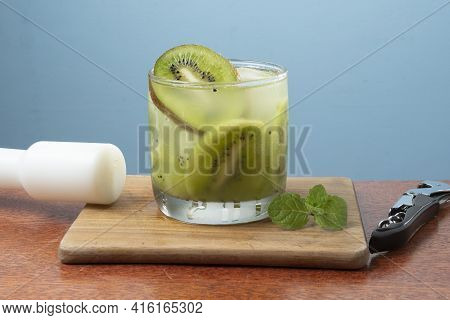 Alcoholic Drink Caipirinha Based On Kiwi And Aguardente Distilled Cocktail Drink And Fruits On Blue 