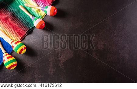 Cinco De Mayo Holiday Background Made From Maracas, Mexican Blanket Stripes Or Poncho Serape On Dark