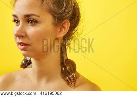 Beautiful Young Woman With A Snail On Her Body On A Yellow Background, Cosmetology Procedure