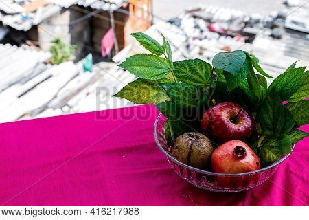 Stock Photo Of An Apple, Pomegranate And Sapodilla Fruit Kept In A Glass Bowl On Pink Background Dec