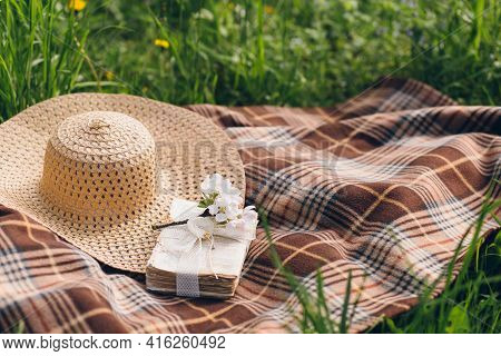 Hat And A Book Lie On A Blanket During A Picnic