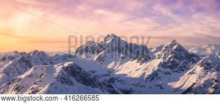 Aerial View From Airplane Of Blue Snow Covered Canadian Mountain Landscape In Winter. Colorful Pink 