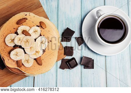 Pancakes With Banana And Nuts On A Wooden Board, Blue Light Background, Top View