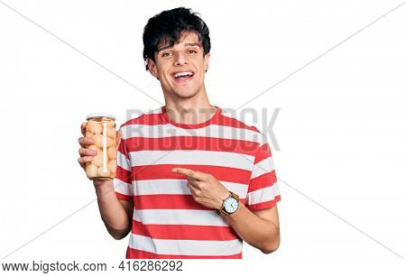 Handsome hipster young man holding bottle with boiled potatoes smiling happy pointing with hand and finger 