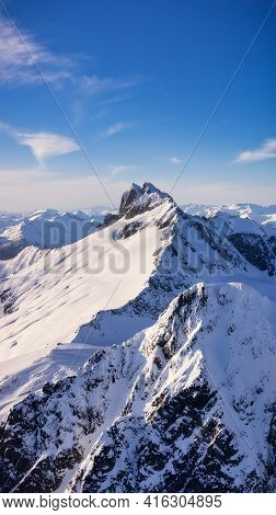 Aerial View From Airplane Of Blue Snow Covered Canadian Mountain Landscape In Winter. Colorful Blue 