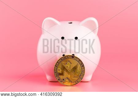 Piggy Bank And Golden Monero Coin Cryptocurrency On A Pink Background. Bitcoin Mining Concept