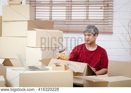 Fat Man With White Hair Is Packing Products Into Paper Boxes For Delivery The Concept Of Small Entre