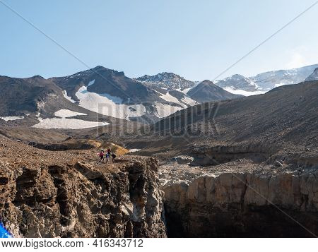 View Of The Opasny Canyon Near The Mutnovsky Volcano. Tourists Stand Near The Edge Of The Canyon And
