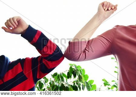 Boy And Aunt Greet Each Other With Their Elbows On A White Background. New Normalcy, Prevention Of P