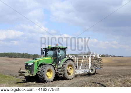 A Large Modern John Deere Tractor Tows A Cultivator In A Field
