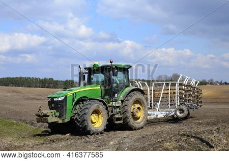 A Large Modern John Deere Tractor Tows A Cultivator In A Field