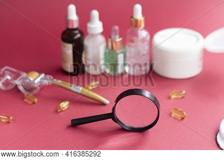 Magnifying Glass Against The Background Of Blurred Face Serums And Dermoroller