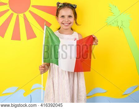 Little Girl On A Bright Background With Italian Flag. The Concept Of Summer, Beach Holidays And Vaca