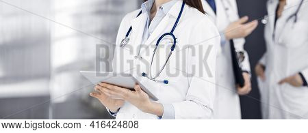 Unknown Woman Doctor Iusing Tablet Computer In Her Hands, While Standing In Clinic. Medicine Concept