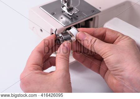 The Tailor Inserts The Babine Into The Metal Spool Holder Of The Sewing Machine.