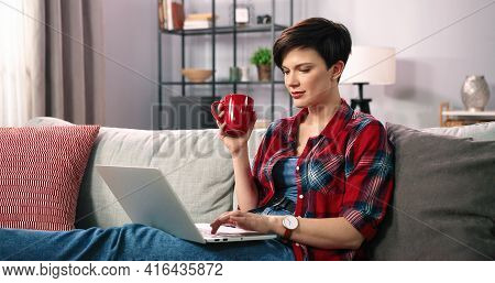 Portrait Of Positive Cheerful Beautifiul Girl With Short Brunette Hair Holding Mug With Beverage And