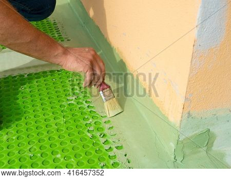 Worker Applies Waterproofing With A Small Brush