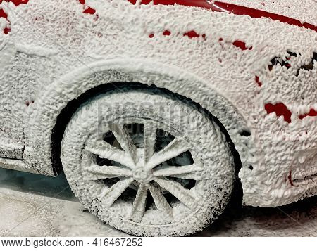 Front Right Wheel Of A Red Car On Which Foam Is Applied To Wash A Car At A Self-service Car Wash.