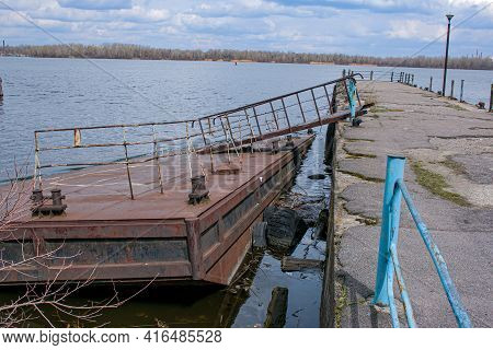 Old Rusty Sunken Pier In The Water On The Territory Of The River Port. Old Sunken Rusty Structure On