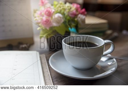 Coffee Break Time. A Cup Of Coffee, Diary, Clock, Calendar, And Rose Flower Vase Place On Home Offic
