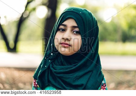 Portrait Of Happy Little Muslim Girls Child With Hijab Dress Smiling And Looking At Camera In The Pa