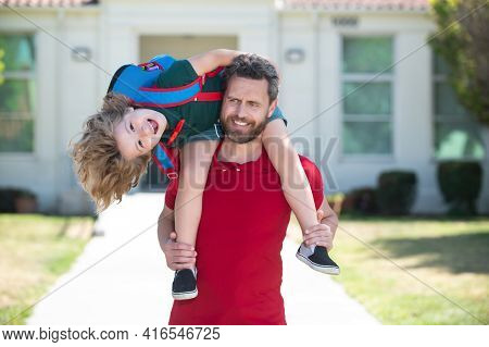School Boy Going To School With Father. Man Giving Son Piggyback Ride After Come Back From School