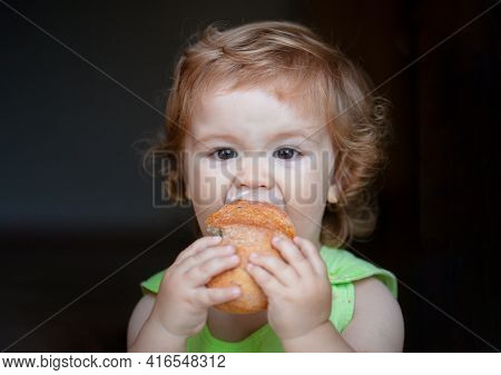 Portrait Of Funny Baby With Bread In Her Hands Eating. Cute Toddler Child Eating Sandwich, Self Feed