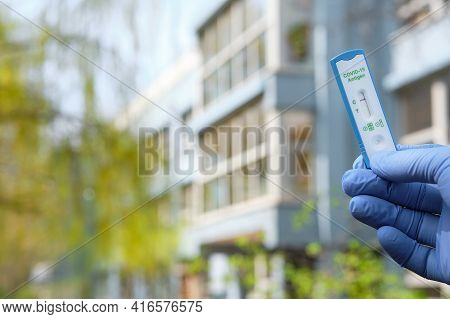 Hand Holds Quick Test Outdoors, With Office, School Or Kindergarden Building Out Of Focus. Express C