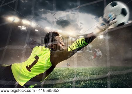 African Male Soccer Or Football Player, Goalkeeper In Action At Stadium. Young Man Catching Ball, Tr