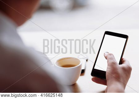 Businessman Hand Holding A Phone With Isolated Screen Against Moke Up And Drink Coffee In The Coffee