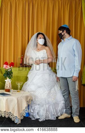 During The Chupa Ceremony In The Synagogue, The Masked Jewish Bride And Groom Stand Side By Side.