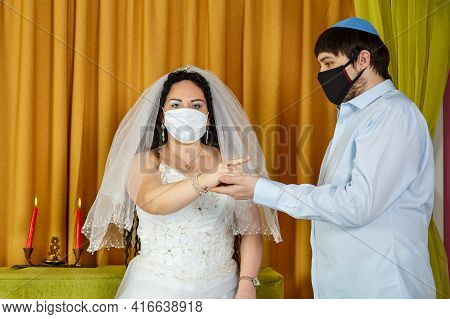 During A Chuppah Ceremony At A Jewish Wedding In A Synagogue, The Groom Puts A Ring On The Brides In
