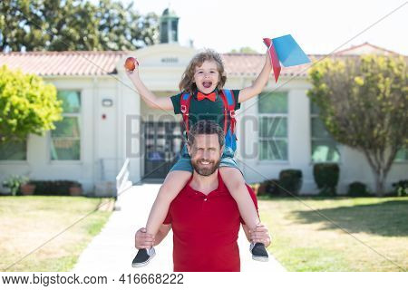 Man And Excited Amazed Child Son Piggyback Near School. Father And Son Run With Father After Come Ba