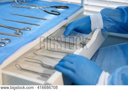 Doctor Putting Pott's Scissors Into Drawer Indoors, Closeup. Table With Different Surgical Instrumen
