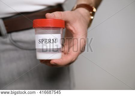 Donor Holding Container With Sperm On Beige Background, Closeup. Space For Text