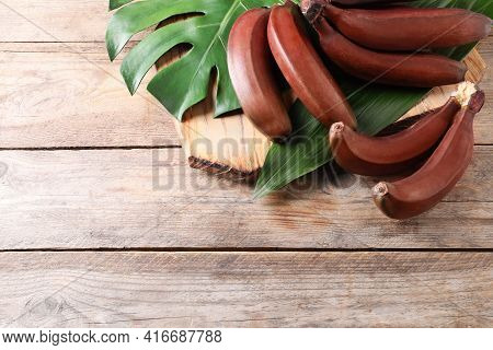 Delicious Red Baby Bananas On Wooden Table, Flat Lay. Space For Text