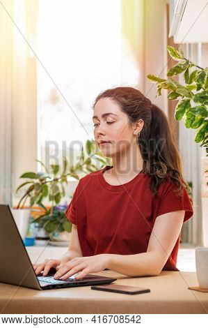 Freelance.young Pretty Woman Typing On A Laptop, Siyad At The Desk. Home Decor, The Sun Outside The 