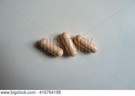 Top View Of Three Pink Capsules Of Probiotic Dietary Supplement