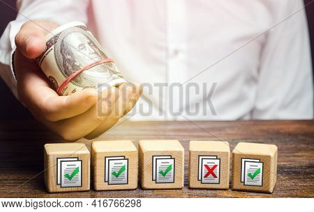 Man Holds Money Above Of Blocks With Permits Documents. Artificial Bureaucratic Obstacles, Corruptio