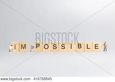 Miniature  People Worker Team On Impossible Word In Wooden Alphabet Letters
