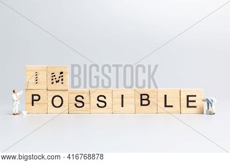Miniature  People Worker Team On Impossible Word In Wooden Alphabet Letters