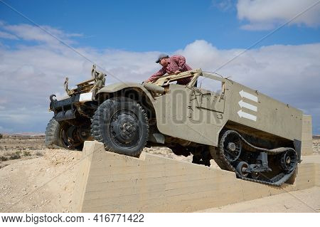 A Man In A Baseball Cap And Dark Glasses In An Old Military Vehicle
