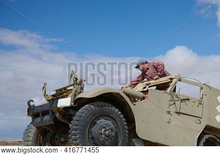 A Man In A Baseball Cap And Dark Glasses In An Old Military Vehicle