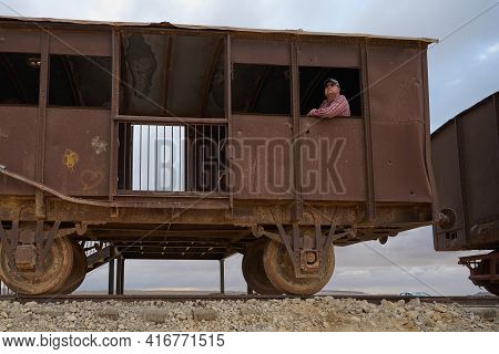 A Man In A Baseball Cap And Dark Glasses In An Old Military Vehicle