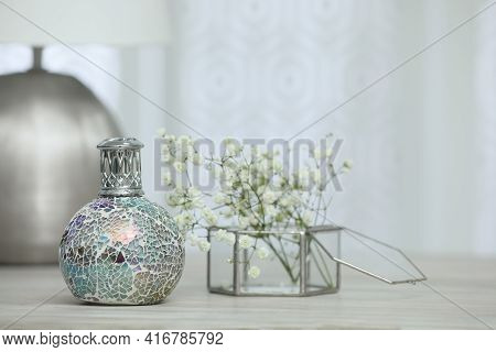 Beautiful Catalytic Purifying Lamp And Flowers On Wooden Table, Space For Text