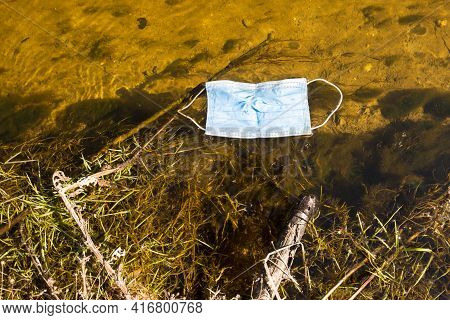 One Used Madical Mask Floating In A Small River, Close Up.